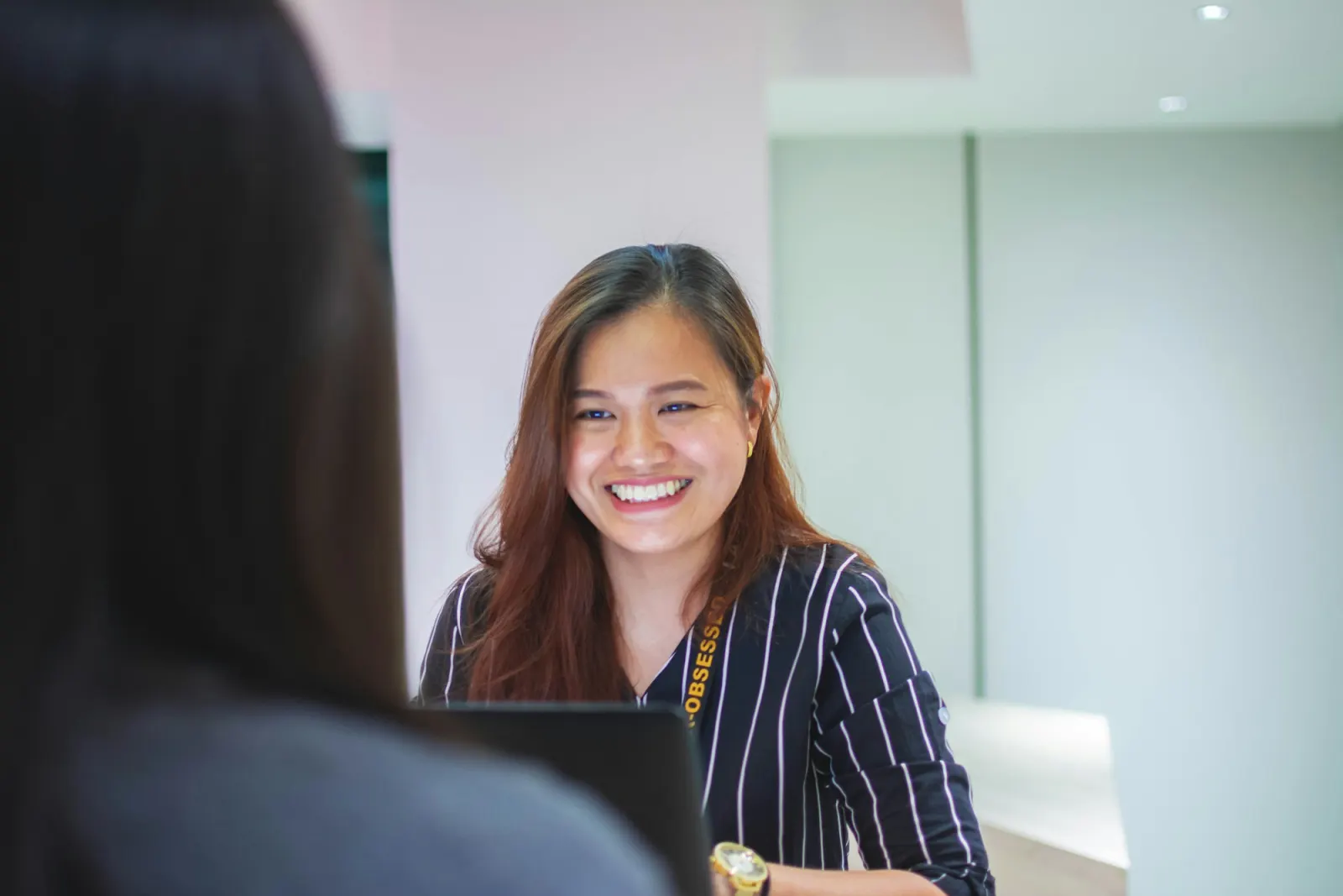 Receptionist smiling while helping a visitor at the front desk