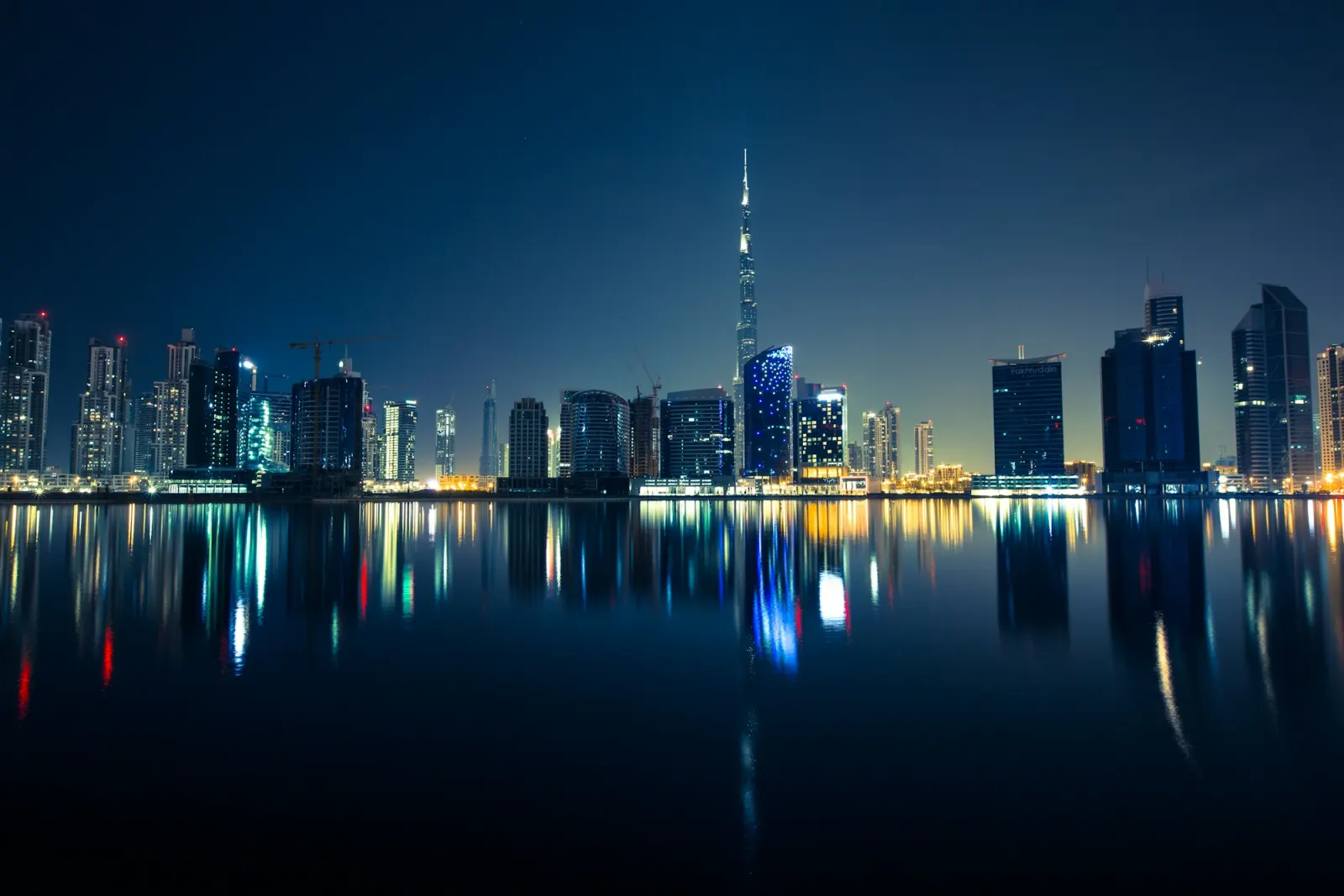 Dubai skyline at night, reflected in still water