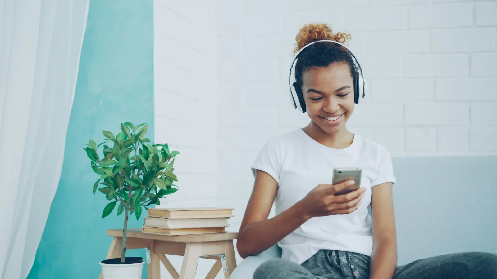 Young woman with headphones checking a fitness app on her phone at home
