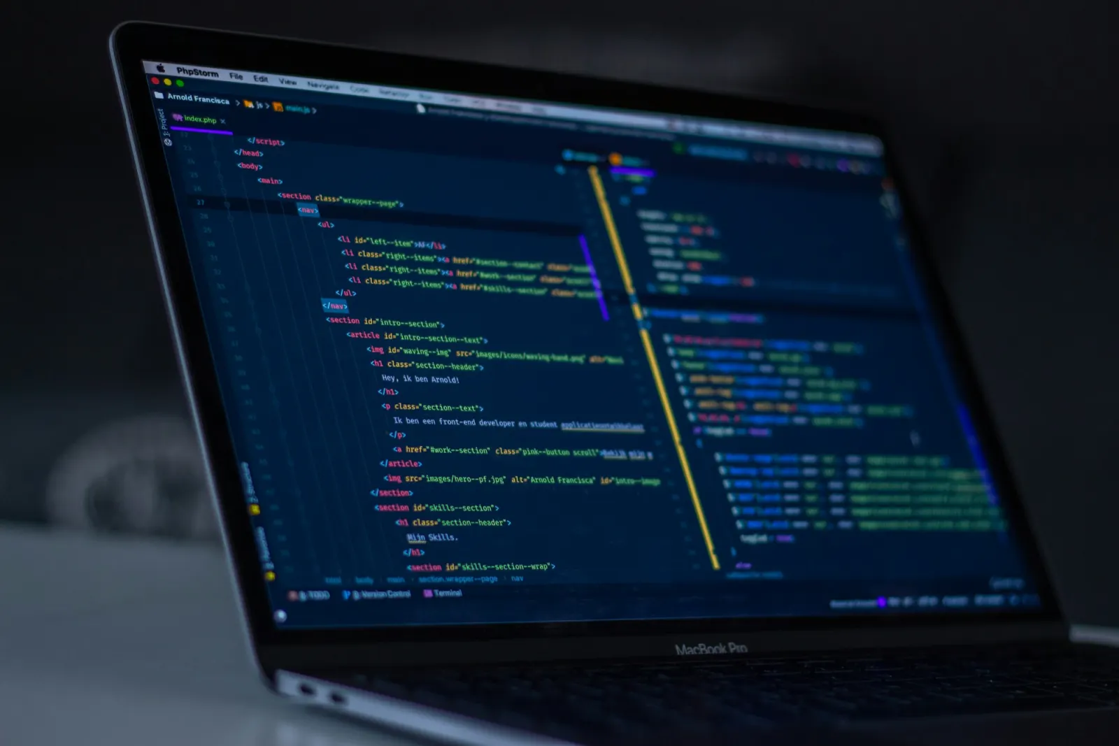 Laptop on a dark desk showing source code in an editor